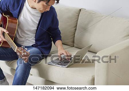 Japanese man playing guitar at home View Large Photo Image Picture - Japanese man playing guitar at home. Fotosearch