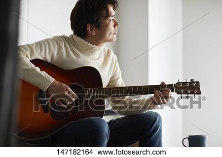 Japanese man playing guitar at home View Large Photo Image Picture - Japanese man playing guitar at home. Fotosearch