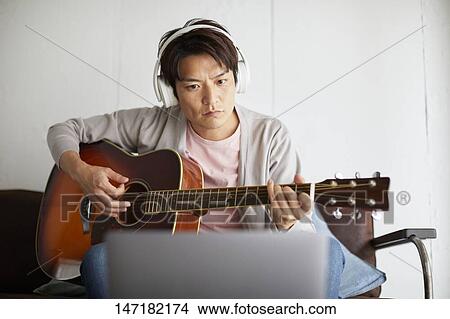 Japanese man playing guitar at home View Large Photo Image Picture - Japanese man playing guitar at home. Fotosearch