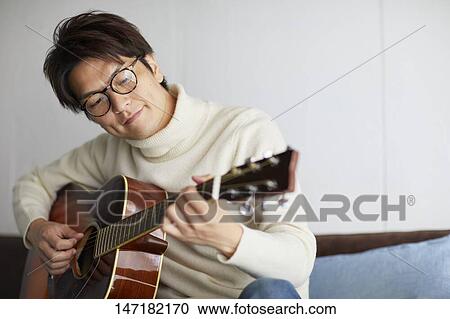 Japanese man playing guitar at home View Large Photo Image Stock Image - Japanese man playing guitar at home. Fotosearch