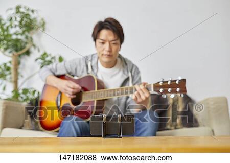 Japanese man playing guitar at home View Large Photo Image Stock Photo - Japanese man playing guitar at home. Fotosearch