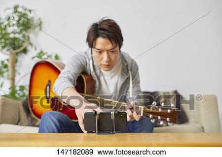Japanese man playing guitar at home View Large Photo Image Stock Photo - Japanese man playing guitar at home. Fotosearch