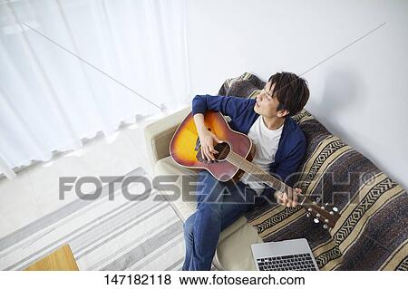 Japanese man playing guitar at home View Large Photo Image Stock Photo - Japanese man playing guitar at home. Fotosearch