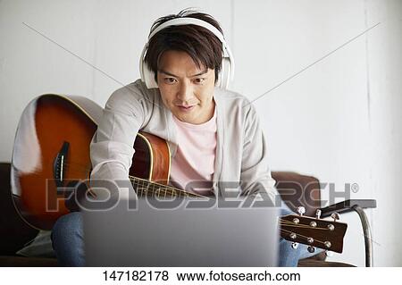 Japanese man playing guitar at home View Large Photo Image Stock Photo - Japanese man playing guitar at home. Fotosearch