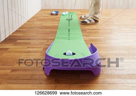Stock Photo - Japanese man training for golf at home. Fotosearch