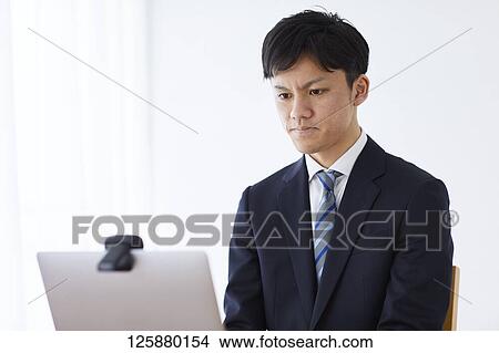 Picture - Japanese man working from home. Fotosearch