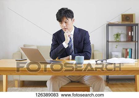 Stock Image - Japanese man working from home. Fotosearch