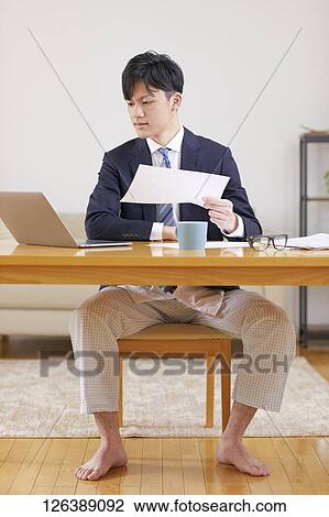 Stock Image - Japanese man working from home. Fotosearch
