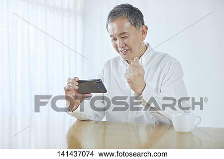Picture - Japanese Middle Aged Man Smiling In The Room. Fotosearch