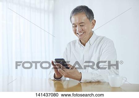 Stock Image - Japanese Middle Aged Man Smiling In The Room. Fotosearch