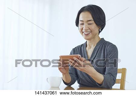 Stock Image - Japanese Middle Aged Woman Smiling In The Room. Fotosearch