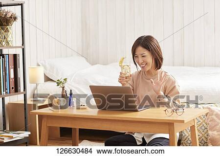 Japanese woman drinking at home remote drinking View Large Photo Image Picture - Japanese woman drinking at home remote drinking. Fotosearch
