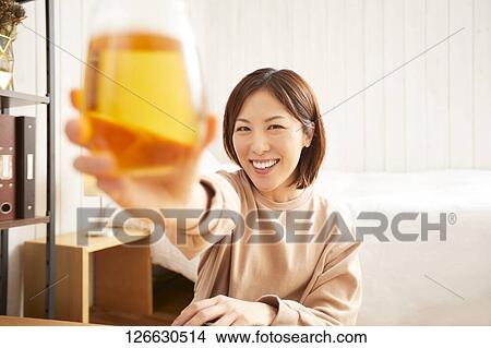 Picture - Japanese woman drinking at home remote drinking. Fotosearch