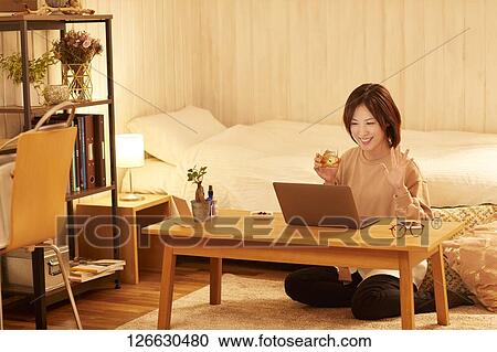 Stock Image - Japanese woman drinking at home remote drinking. Fotosearch