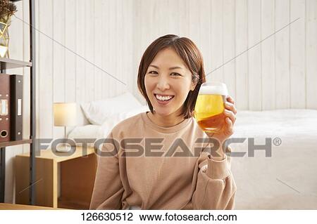 Stock Image - Japanese woman drinking at home remote drinking. Fotosearch