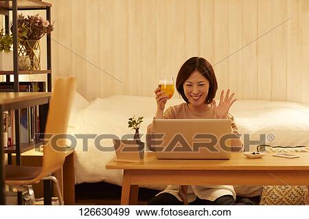 Stock Photo - Japanese woman drinking at home remote drinking. Fotosearch