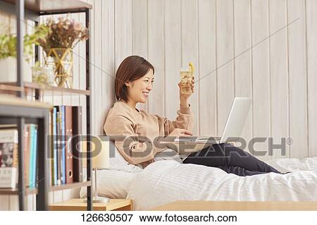 Stock Photo - Japanese woman drinking at home remote drinking. Fotosearch