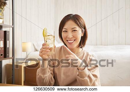 Stock Photo - Japanese woman drinking at home remote drinking. Fotosearch