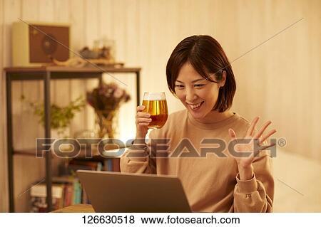 Stock Photo - Japanese woman drinking at home remote drinking. Fotosearch