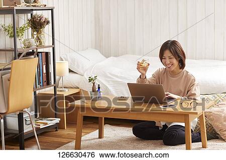 Stock Photograph - Japanese woman drinking at home remote drinking. Fotosearch