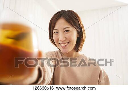 Stock Photograph - Japanese woman drinking at home remote drinking. Fotosearch