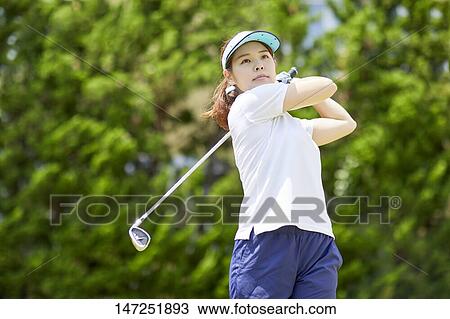 Stock Image - Japanese woman practicing golf in the garden. Fotosearch