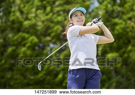 Stock Photo - Japanese woman practicing golf in the garden. Fotosearch