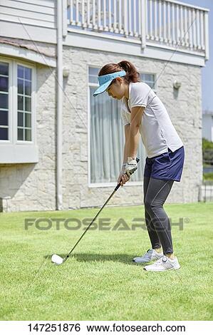 Stock Photograph - Japanese woman practicing golf in the garden. Fotosearch