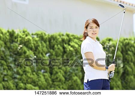 Stock Photograph - Japanese woman practicing golf in the garden. Fotosearch