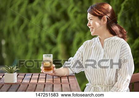 Stock Image - Japanese woman relaxing in the garden. Fotosearch