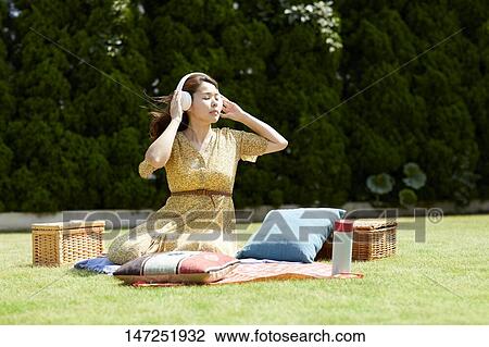 Stock Image - Japanese woman relaxing in the garden. Fotosearch