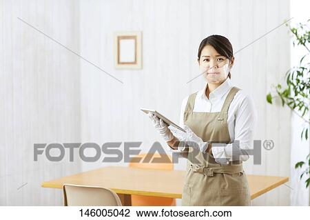 Stock Image - Japanese woman wearing face shield. Fotosearch