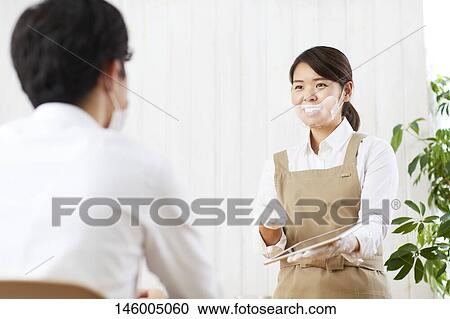 Stock Image - Japanese woman wearing face shield. Fotosearch