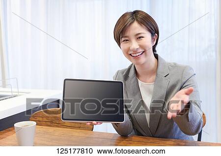 Stock Image - Japanese woman working from home. Fotosearch