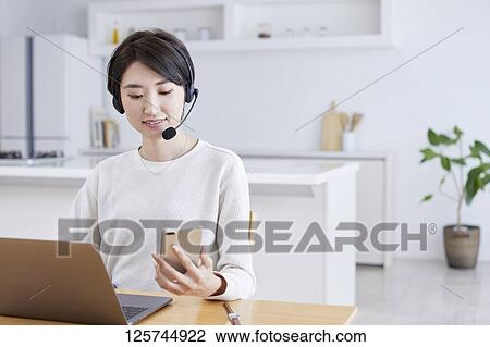 Stock Image - Japanese woman working from home. Fotosearch