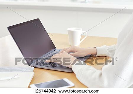 Stock Image - Japanese woman working from home. Fotosearch