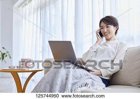 Stock Image - Japanese woman working from home. Fotosearch