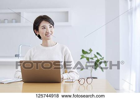 Stock Photo - Japanese woman working from home. Fotosearch