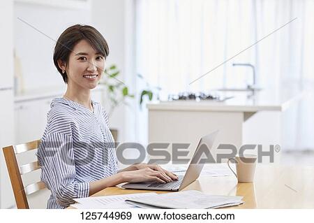 Stock Photo - Japanese woman working from home. Fotosearch
