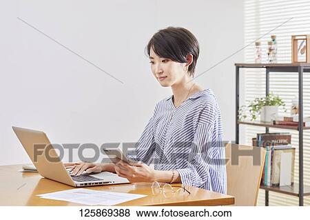 Japanese woman working from home View Large Photo Image Stock Photo - Japanese woman working from home. Fotosearch