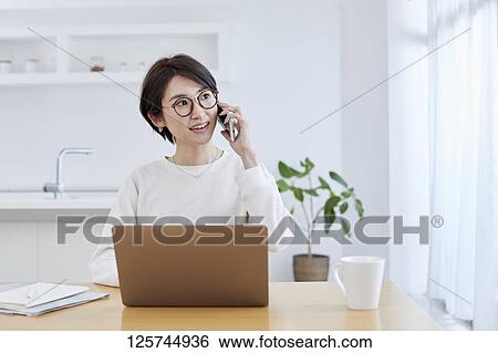 Stock Photograph - Japanese woman working from home. Fotosearch