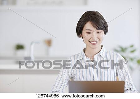 Stock Photograph - Japanese woman working from home. Fotosearch
