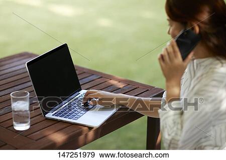 Japanese woman working with laptop in the garden View Large Photo Image Stock Photo - Japanese woman working with laptop in the garden. Fotosearch