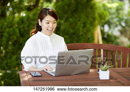 Japanese woman working with laptop in the garden View Large Photo Image Stock Photograph - Japanese woman working with laptop in the garden. Fotosearch
