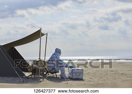 Stock Photo - Man in a hazmat suit at the beach. Fotosearch