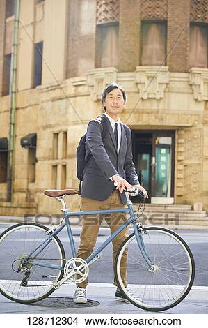Picture - Middle Aged Japanese Businessman Riding A Bicycle. Fotosearch
