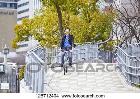 Picture - Middle Aged Japanese Businessman Riding A Bicycle. Fotosearch