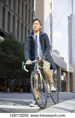 Stock Image - Middle Aged Japanese Businessman Riding A Bicycle. Fotosearch