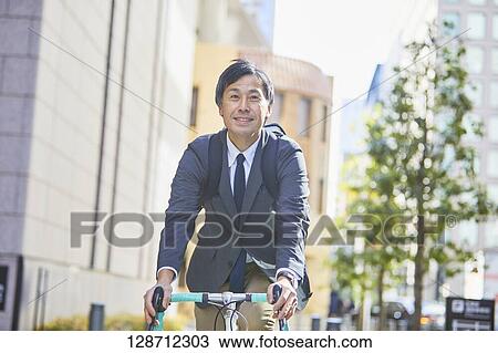 Stock Image - Middle Aged Japanese Businessman Riding A Bicycle. Fotosearch