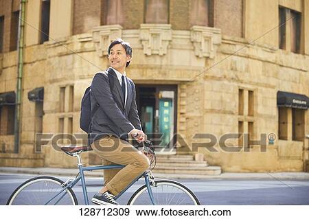 Middle Aged Japanese Businessman Riding A Bicycle View Large Photo Image Stock Photo - Middle Aged Japanese Businessman Riding A Bicycle. Fotosearch